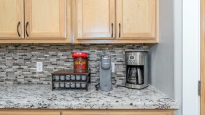 Une cuisine avec des meubles en bois, une machine à café, une machine Keurig et une tasse à café McCafé.