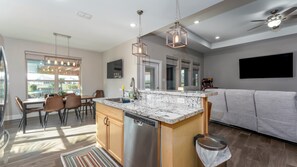 A modern kitchen with a central island, stainless steel appliances, and pendant lighting.