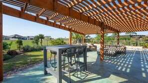 An outdoor patio with a pergola, seating area, and a table.