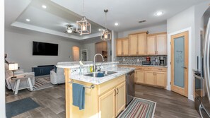 A modern kitchen with a central island, wooden cabinets, and stainless steel appliances.