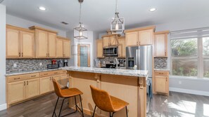 A modern kitchen with wooden cabinets, stainless steel appliances, and a marble countertop.