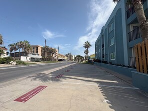 Eine Straße mit einem blauen Gebäude, Palmen und blauem Himmel.