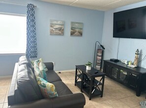 Ein Wohnzimmer mit einer Couch, einem Couchtisch, einem Fernseher und Kunstwerken an der Wand.