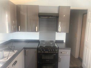 A modern kitchen with stainless steel appliances, including a stove and oven, and grey cabinetry. - Caravan Sleeps 6 With Indoor Pool on Site (Clacton-on-Sea)