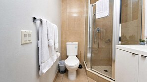 A bathroom with a toilet, a glass shower enclosure, and a towel rack. - RivetStays | The Atmos Gorgeous Suite – 1 Bedroom Condo (Toronto)
