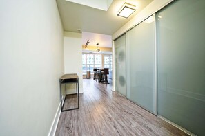 A hallway with a sliding glass door, a small table, and a dining area with chairs and a table in the background. - The Atmos by RivetStays – Spacious 2BR Downtown Condo (Toronto)