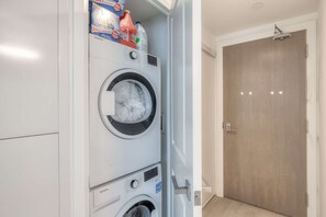 A laundry room with two front-loading washing machines, a door, and a light switch.