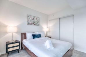 Une chambre d’hôtel comprenant un lit, deux lampes de chevet, une table de chevet, un tableau accroché au mur et une armoire.