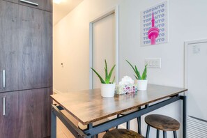 A small kitchenette with a wooden table, two potted aloe plants, and a decorative item on the table. - RivetStays | The York Romantic Suite – 1 Bedroom Condo (Toronto)