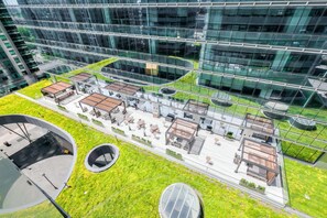 A modern building with a rooftop garden, outdoor seating areas, and a glass facade. - RivetStays | The York Romantic Suite – 1 Bedroom Condo (Toronto)