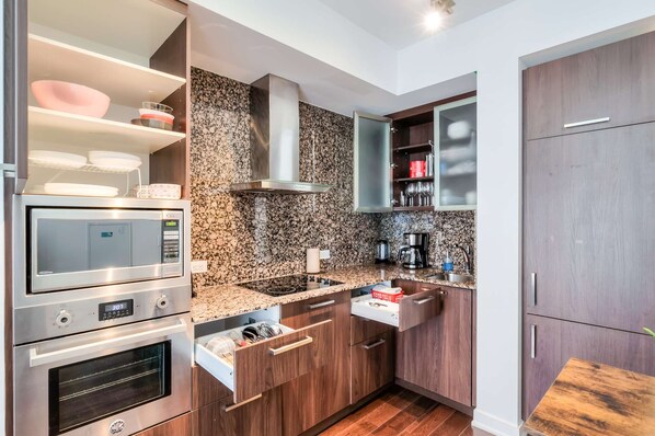 A modern kitchen with built-in appliances, granite countertops, and wooden cabinets. - RivetStays | The York Romantic Suite – 1 Bedroom Condo (Toronto)