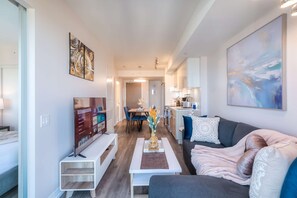 Un salon moderne doté d’un téléviseur à écran plat, d’un canapé, d’une table basse et d’un coin repas avec une table et des chaises.
