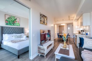 Une chambre d’hôtel moderne dotée d’un grand lit, d’une télévision, d’un coin repas et d’une cuisine.