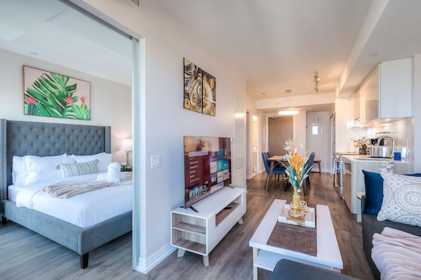 Une chambre d’hôtel moderne dotée d’un grand lit, d’une télévision, d’un coin repas et d’une cuisine.