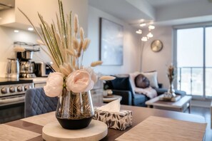 Une cuisine moderne avec un coin repas, agrémentée d’un vase avec des fleurs et des plumes d’herbe des pampas sur la table.