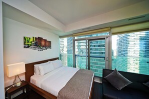 A hotel room with a bed, bedside table, lamp, and a sofa. - RivetStays | The York Honeymoon Suite – Studio Condo (Toronto)