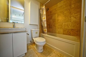 A bathroom with a toilet, a sink, and a bathtub. - RivetStays | The York Honeymoon Suite – Studio Condo (Toronto)