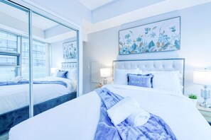 A modern hotel room with a large bed, a glass partition, and a floral painting on the wall. - RivetStays | The York Premier Suite – 1 Bedroom Condo (Toronto)