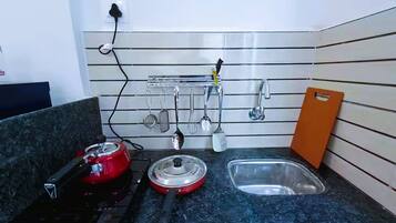 A kitchen with a stove, a sink, and utensils hanging on the wall.