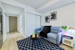 A modern living room with a sofa, a coffee table, and a patterned rug.