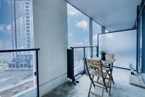 Ein Balkon mit Tisch und Stühlen, einem Blumentopf und Blick auf eine Stadtlandschaft.