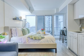 Ein modernes Schlafzimmer mit einem großen Bett, einem Schreibtisch und Blick auf die Stadt durch das Fenster.