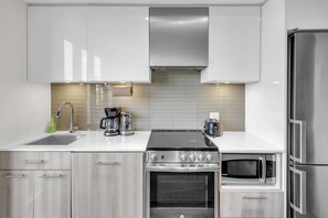 A modern kitchen with stainless steel appliances, a built-in oven, and a microwave. - RivetStays | The Jarvis Deluxe Suite – 1 Bedroom Suite (Toronto)
