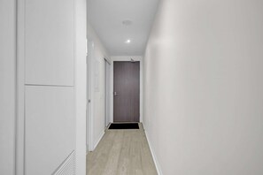 Un couloir étroit aux murs blancs et au plancher en bois.