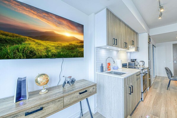 A modern kitchen with wooden cabinets, a built-in island, and a large window with a scenic view. - RivetStays | The Jarvis Executive Suite – 2 Bedroom Suite (Toronto)