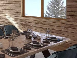 A wooden dining table set with plates, glasses, and cutlery, with a window view of a snowy landscape. - Family apartment with mountain view (Méribel)