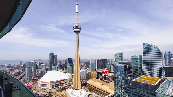 A high-rise building with a distinctive tower, surrounded by modern skyscrapers and a stadium. - RivetStays | The York City Suite – Studio Condo (Toronto)