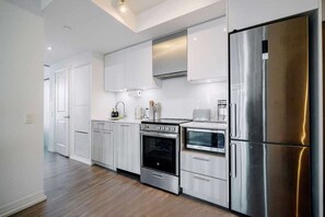 Une cuisine moderne dotée d’appareils électroménagers en acier inoxydable, de meubles blancs et d’un plancher en bois.