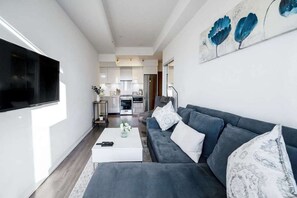 Un salon moderne avec un canapé gris, une table basse et un téléviseur fixé au mur.
