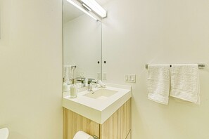 Ein Badezimmer mit Waschbecken, Spiegel und zwei Handtüchern, die an der Wand hängen.