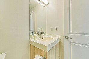Ein modernes Badezimmer mit einem weißen Waschbecken, einem Spiegel und einer Toilette.