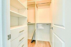 A walk-in closet with open shelves, a hanging rod, and a folded clothes rack. - RivetStays | The Jarvis Elite Suite – 2 Bedroom Suite (Toronto)
