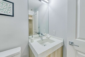 A modern bathroom with a white sink, mirror, and toilet. - RivetStays | The Jarvis Business Suite – Downtown Studio Suite (Toronto)
