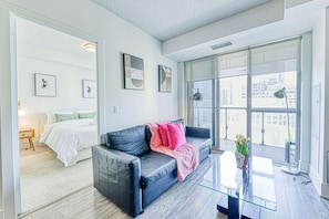 Een moderne woonkamer met een leren bank, een glazen salontafel en uitzicht op de stad door grote ramen.
