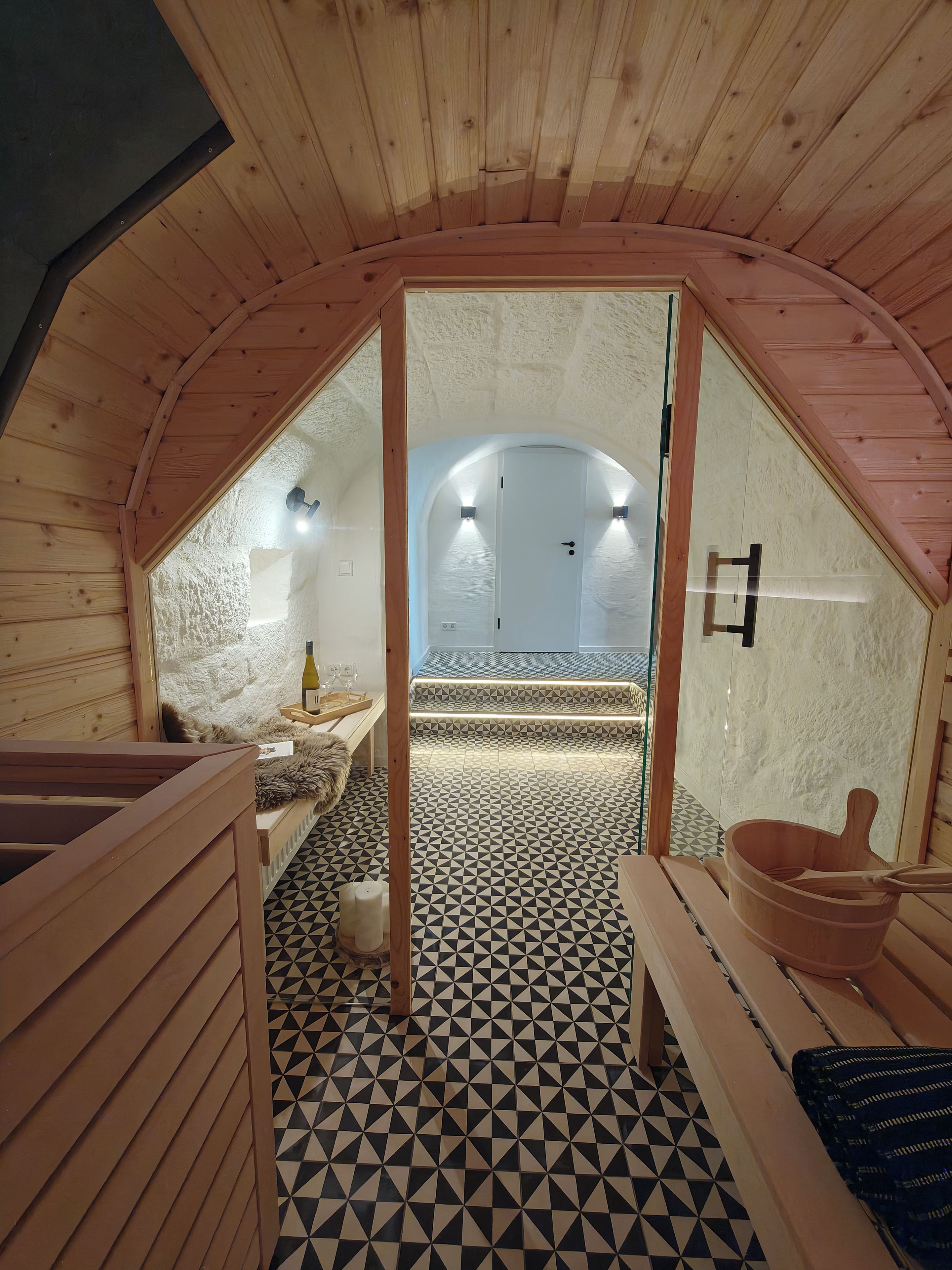 Een sauna met houten wanden, een zwart-wit betegelde vloer en een bak met een wasbak.