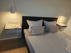 A bedroom with a bed, bedside tables, and a nightstand. - Elbhangsauna - Vacation Rental with Private Sauna and View of the Elbe River (Pirna)