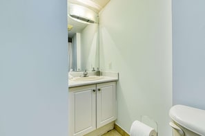 The bathroom vanity, featuring a sink, mirror, and a convenient counter for toiletries.