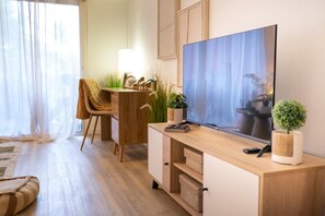 A modern living room with a wooden desk, a television, and a comfortable chair. - Happy Studio Palm court orient bay (SAINT MARTIN)