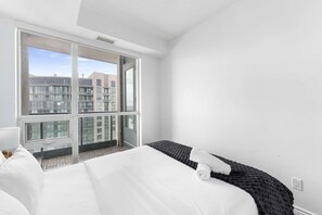 Una camera d'albergo con un'ampia finestra, un letto e vista su altri edifici.