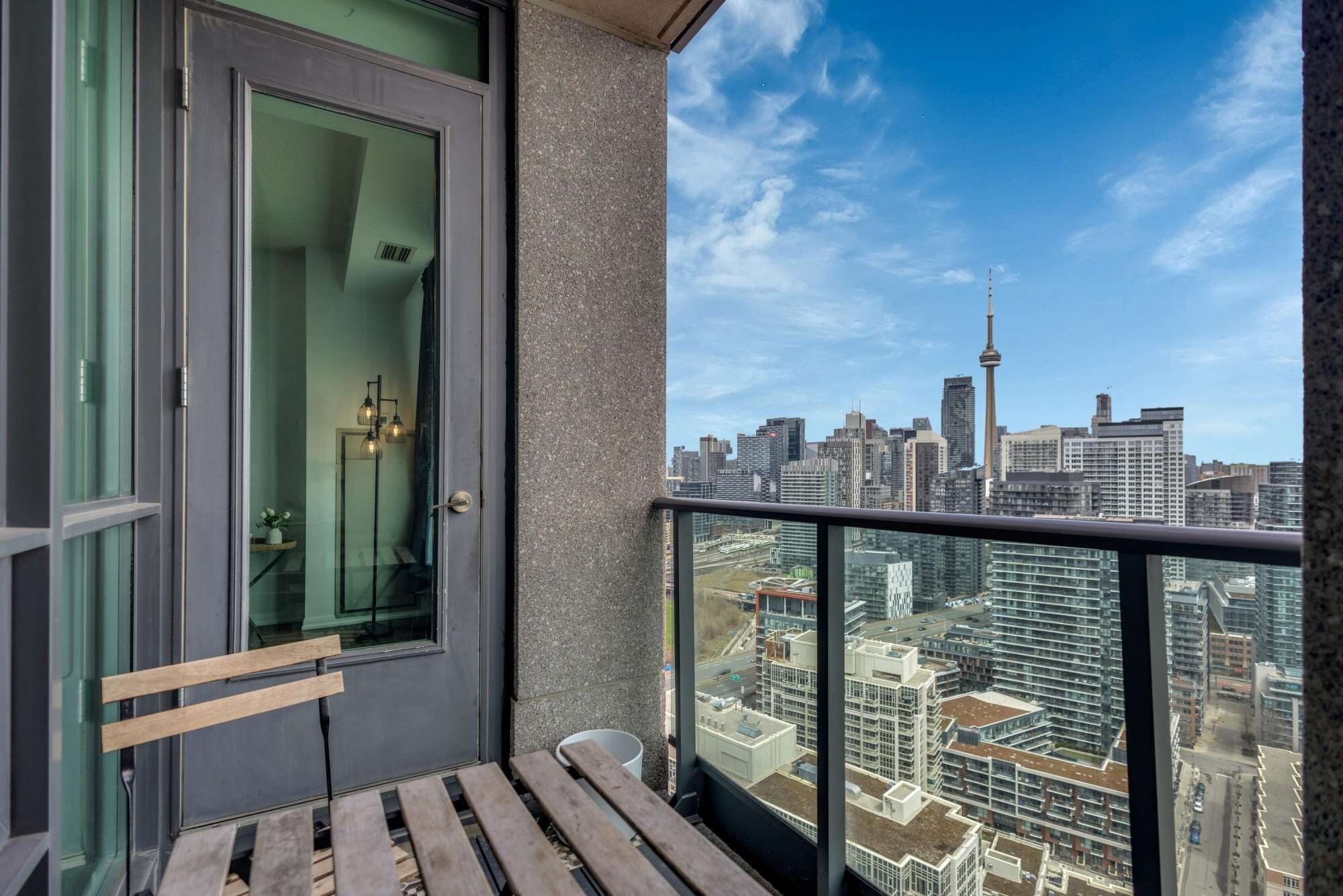 A balcony with a view of a city skyline, including a prominent tower.