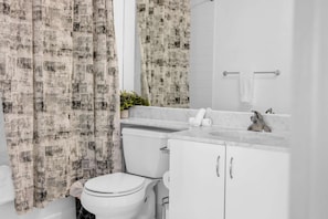 A bathroom with a toilet, a sink, and a mirror. - RivetStays | The Neptune City Suite – 1 Bedroom + Den Condo (Toronto)