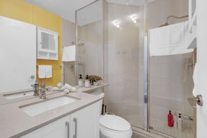 Ein modernes Badezimmer mit Duschkabine aus Glas, Toilette in Weiß und einem Waschtisch mit Spüle und Spiegel.
