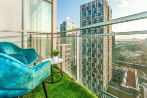 En moderne balkon med en blå stol, et lille bord og en potteplante.