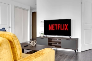 Un salon avec un téléviseur à écran plat fixé au mur, qui affiche le logo de Netflix.
