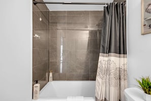 Une salle de bain avec une douche, une baignoire et des toilettes.