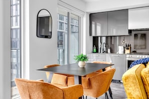 Une cuisine moderne avec des meubles gris, un plan de travail noir et une cuisinière.